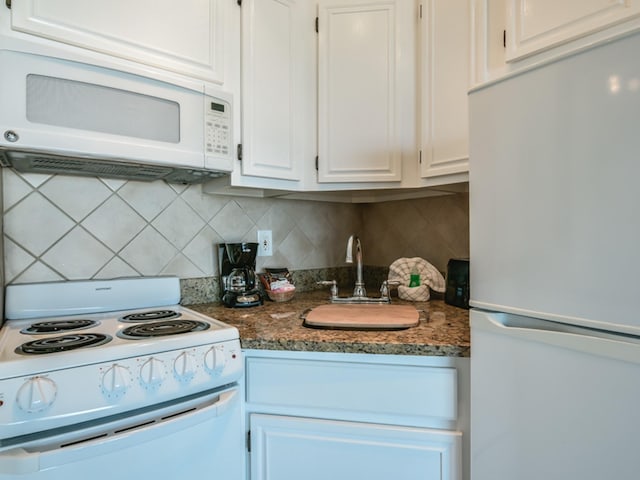 kitchen featuring white appliances, white cabinetry, a sink, and decorative backsplash