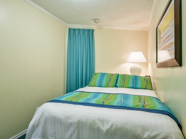 bedroom with a baseboard heating unit, ornamental molding, and a textured ceiling