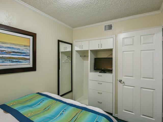 bedroom featuring a closet, visible vents, crown molding, and a textured ceiling