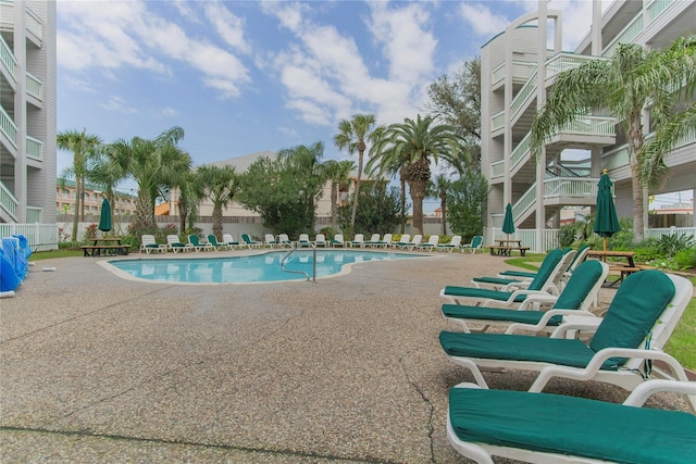 community pool with a patio area and fence