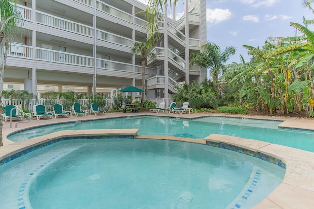 view of swimming pool featuring a patio area, a pool with connected hot tub, and fence