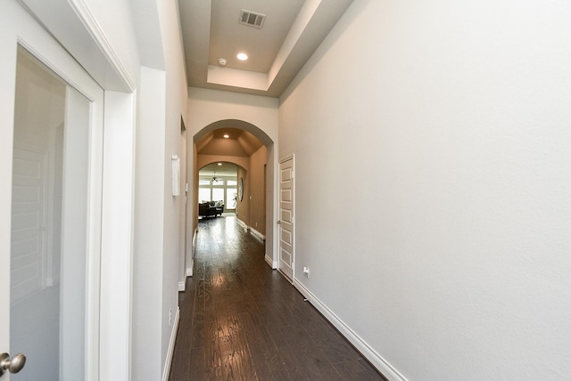 hall featuring arched walkways, recessed lighting, dark wood-type flooring, visible vents, and baseboards