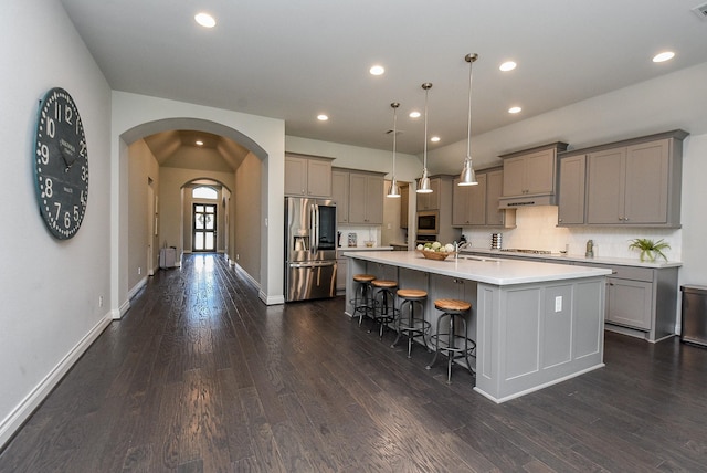 kitchen with stainless steel appliances, arched walkways, gray cabinets, and a large island