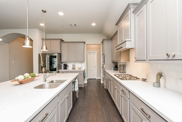 kitchen with arched walkways, stainless steel appliances, a sink, visible vents, and custom range hood