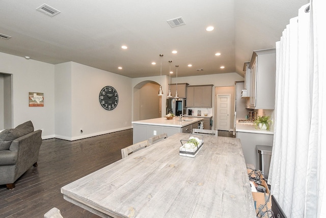 kitchen featuring gray cabinets, visible vents, a center island with sink, and a sink