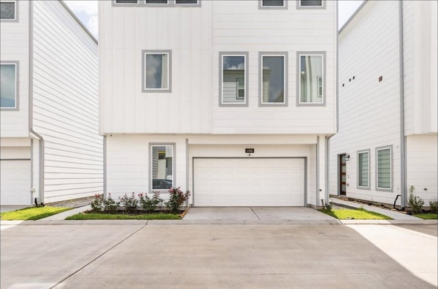 townhome / multi-family property with concrete driveway, board and batten siding, and an attached garage