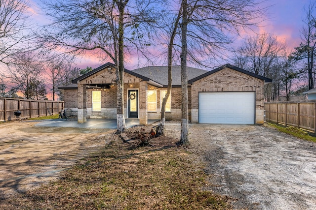 view of front of house featuring brick siding, a shingled roof, fence, a garage, and driveway