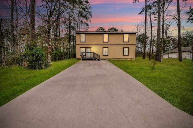 view of front of home with a yard, concrete driveway, and stucco siding