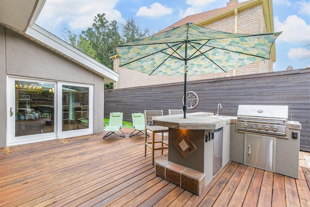 wooden deck with a grill, fence, exterior kitchen, a bar, and a sink