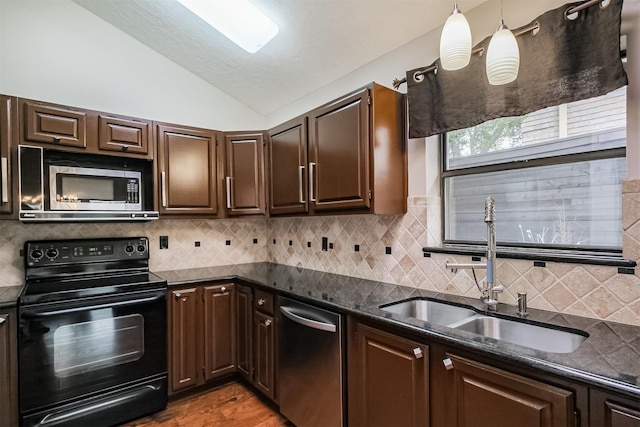 kitchen with stainless steel appliances, hanging light fixtures, vaulted ceiling, a sink, and dark brown cabinetry