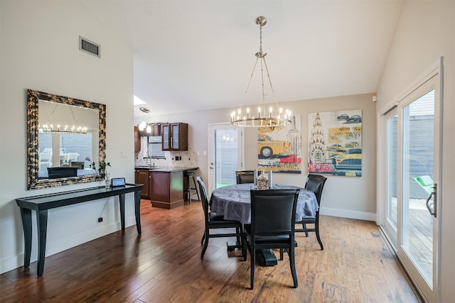 dining space featuring baseboards, visible vents, a chandelier, and dark wood-style flooring