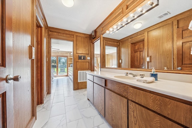 bathroom with marble finish floor, wood walls, vanity, and visible vents