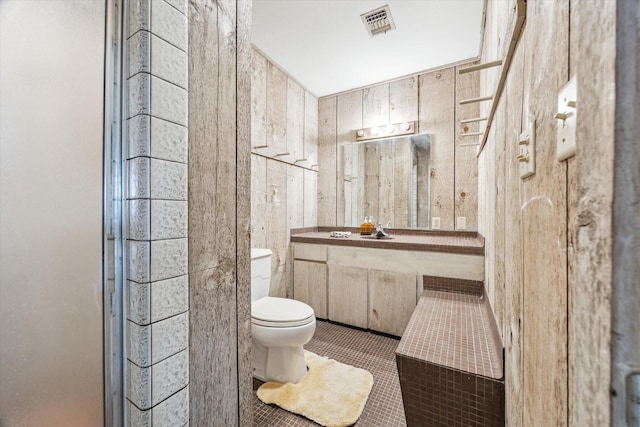 bathroom featuring toilet, wood walls, visible vents, and tile patterned floors