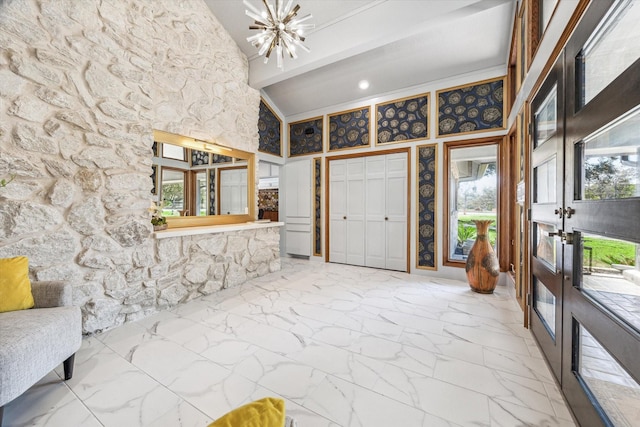 foyer entrance featuring a chandelier, marble finish floor, beamed ceiling, and high vaulted ceiling