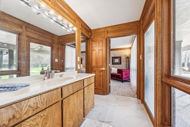 ensuite bathroom with marble finish floor, wood walls, connected bathroom, and vanity