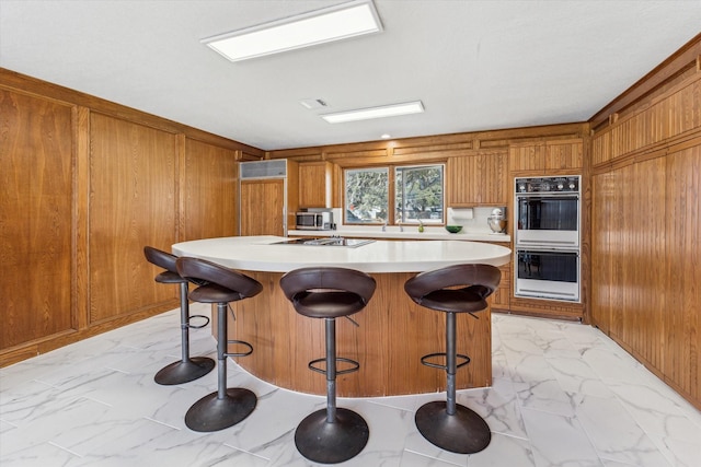 kitchen featuring light countertops, marble finish floor, brown cabinets, and a kitchen island