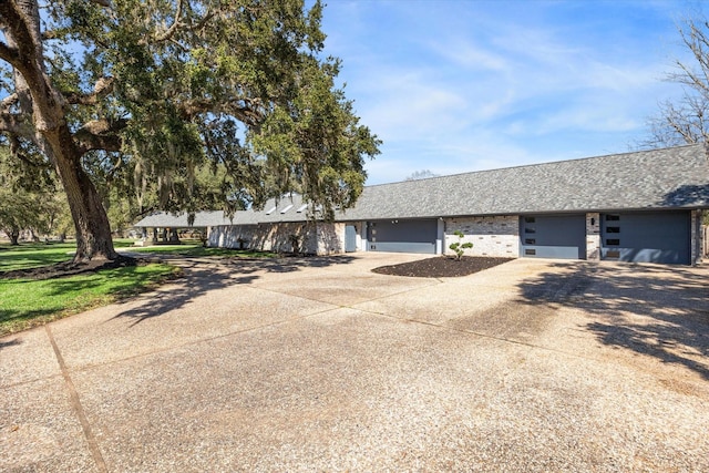 ranch-style house featuring a garage, driveway, and roof with shingles