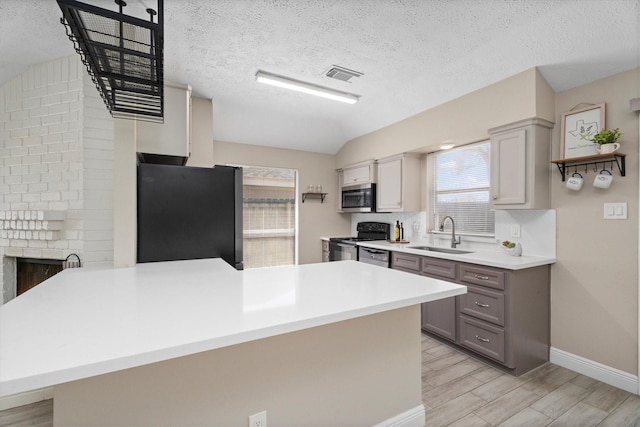 kitchen with visible vents, appliances with stainless steel finishes, a peninsula, gray cabinets, and a sink