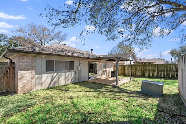 back of house with a patio, a lawn, a fenced backyard, and board and batten siding