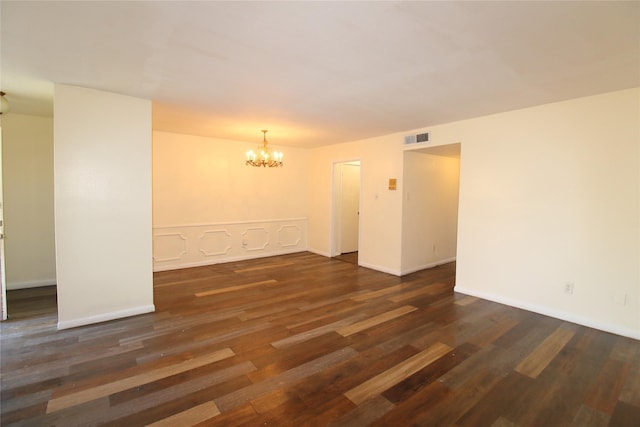 spare room with an inviting chandelier, baseboards, visible vents, and dark wood-style flooring