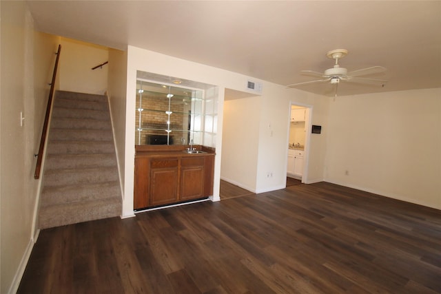 unfurnished room featuring ceiling fan, stairs, baseboards, and dark wood finished floors