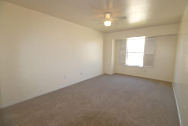 carpeted empty room with ceiling fan and baseboards