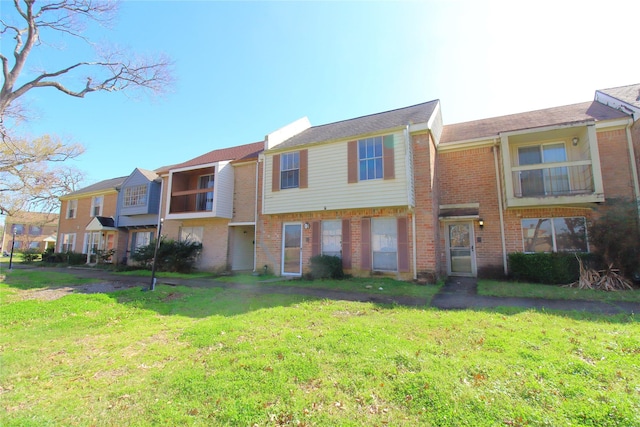 townhome / multi-family property featuring a front yard and brick siding