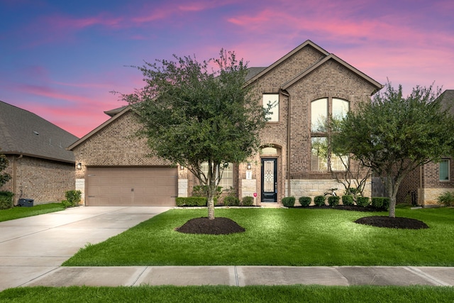 french country inspired facade with a yard, concrete driveway, and brick siding