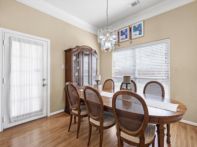 dining room featuring baseboards, visible vents, ornamental molding, light wood-style floors, and a chandelier