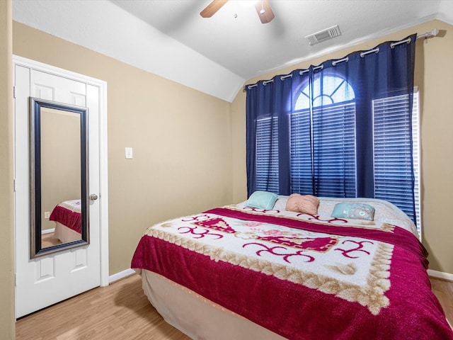 bedroom featuring visible vents, a ceiling fan, vaulted ceiling, wood finished floors, and baseboards