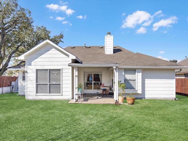 rear view of property featuring a yard, a chimney, fence, and a patio