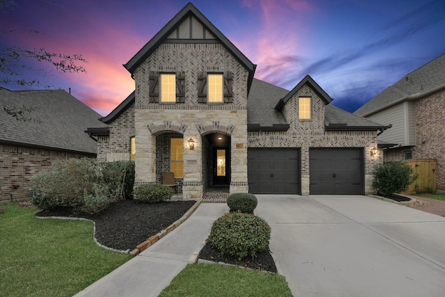 french country style house featuring a garage, concrete driveway, brick siding, and a shingled roof