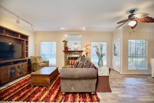 living room with crown molding, a textured ceiling, and a glass covered fireplace