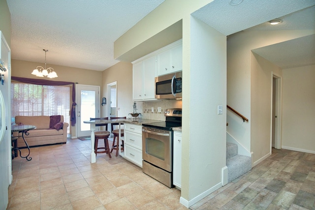 kitchen with white cabinets, a kitchen breakfast bar, decorative light fixtures, light stone countertops, and stainless steel appliances