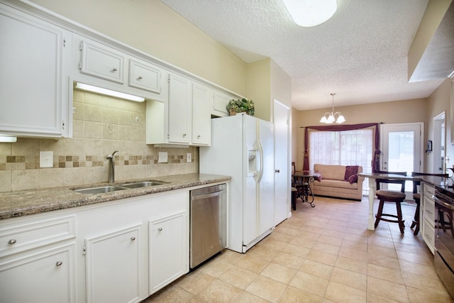 kitchen featuring stainless steel appliances, a sink, white cabinets, tasteful backsplash, and decorative light fixtures