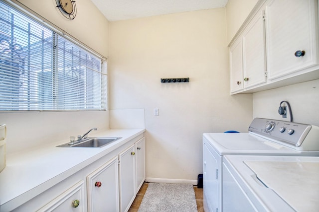 laundry room featuring independent washer and dryer, a sink, cabinet space, and baseboards