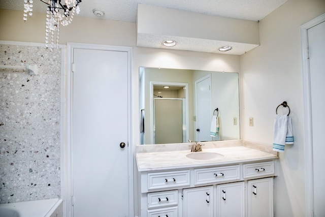 full bathroom featuring a bath, a shower with door, a textured ceiling, and vanity