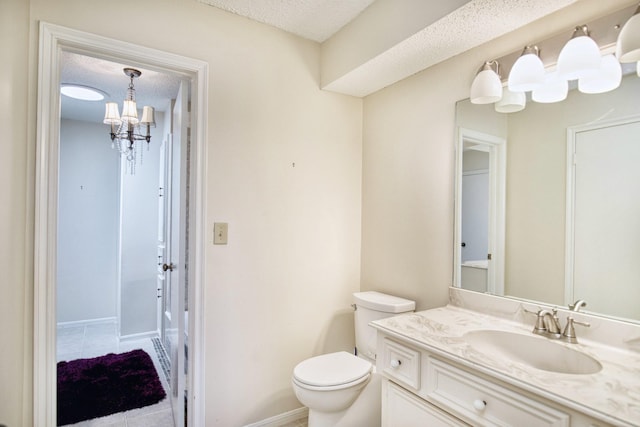 bathroom with toilet, vanity, a textured ceiling, a chandelier, and baseboards