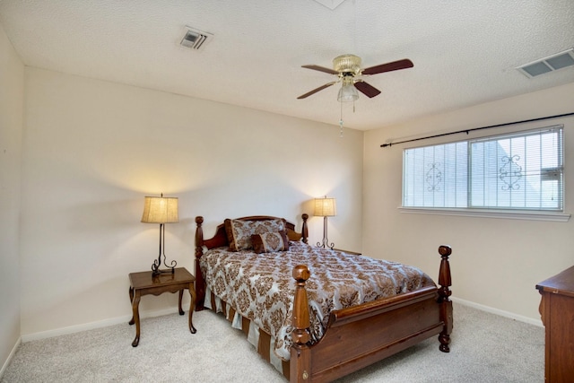 bedroom featuring a textured ceiling, baseboards, visible vents, and light colored carpet