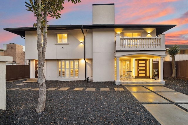 rear view of house with a patio area, fence, a balcony, and stucco siding