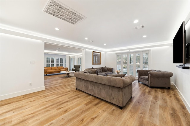 living room featuring light wood-style flooring, visible vents, and baseboards