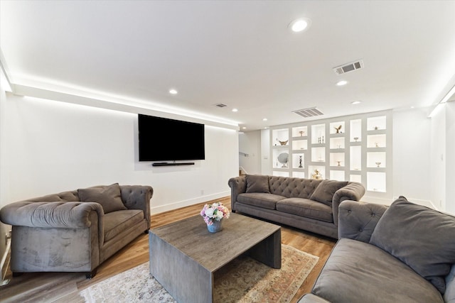 living room with light wood finished floors, visible vents, and recessed lighting