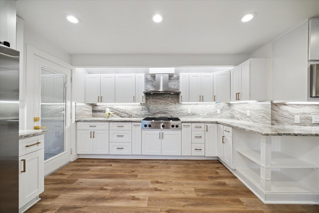 kitchen with open shelves, white cabinetry, appliances with stainless steel finishes, light wood-type flooring, and wall chimney exhaust hood