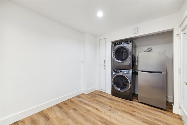 washroom with laundry area, light wood-style flooring, baseboards, and stacked washer / dryer