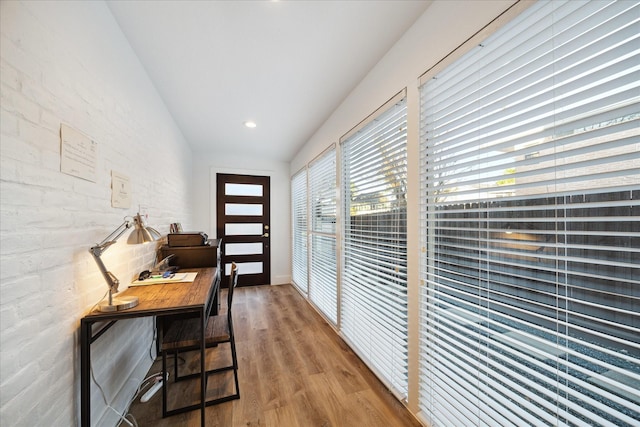 doorway to outside featuring recessed lighting, brick wall, and wood finished floors