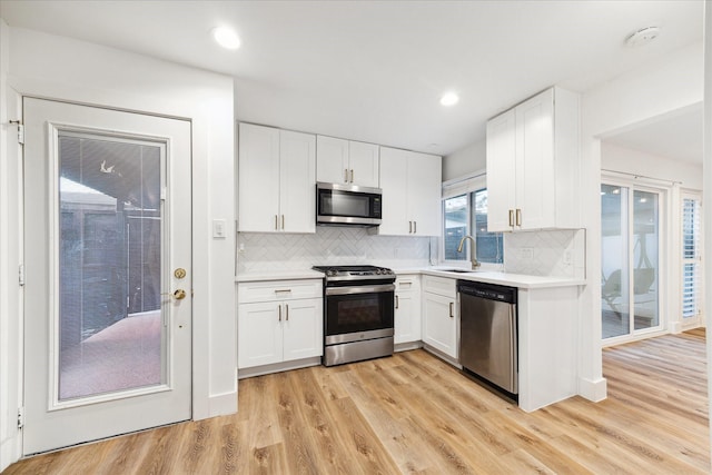 kitchen with a sink, appliances with stainless steel finishes, white cabinets, and light countertops