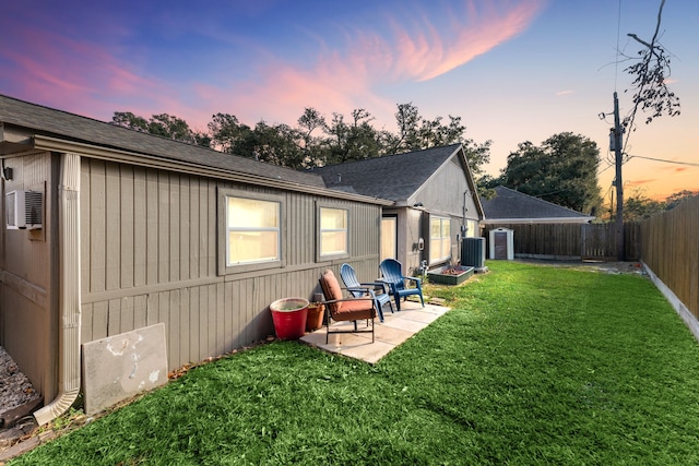 rear view of property with a patio, a fenced backyard, roof with shingles, cooling unit, and a yard