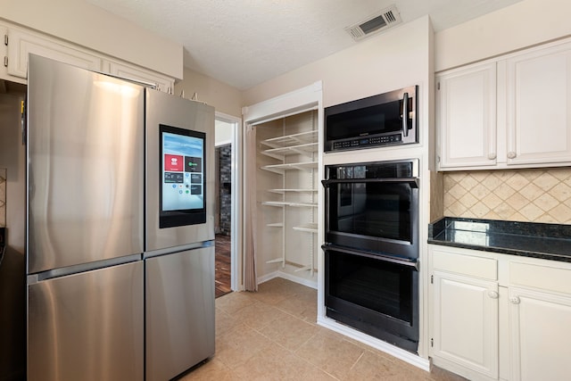 kitchen with stainless steel appliances, visible vents, white cabinetry, and tasteful backsplash