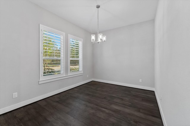 unfurnished room featuring dark wood-style floors, an inviting chandelier, and baseboards