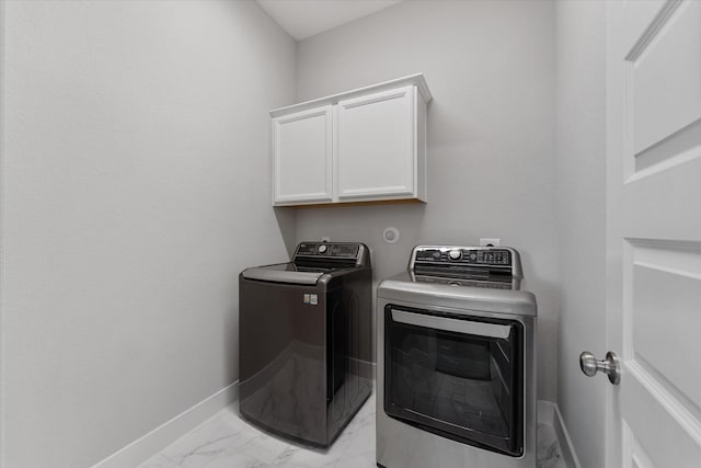 laundry room featuring washing machine and dryer, marble finish floor, cabinet space, and baseboards